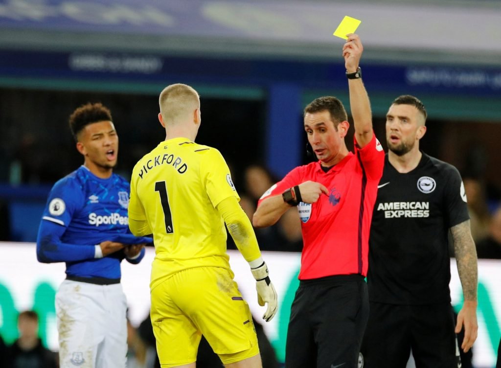 Everton's Jordan Pickford is shown a yellow card by referee David Coote